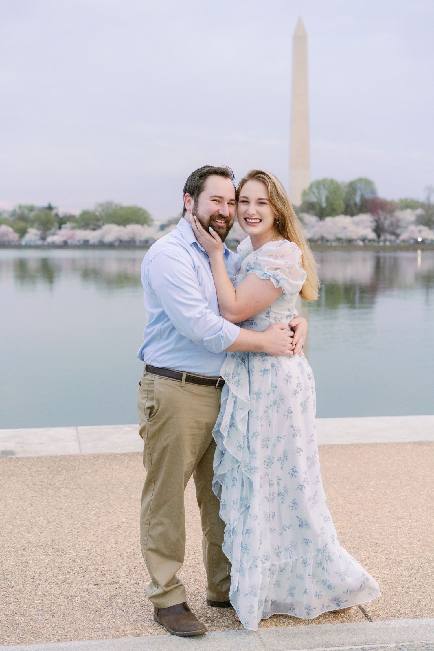 Happy couple laughing together at Tidal Basin with Washington Monument backdrop.