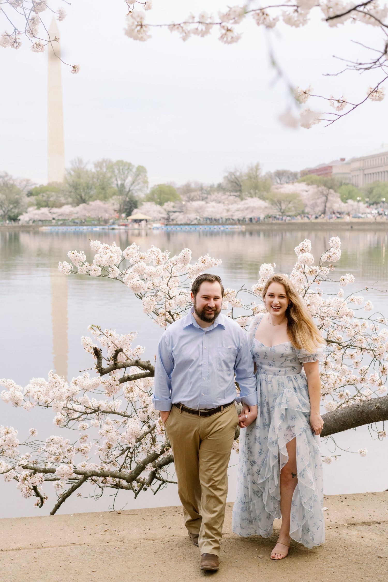 A springtime portrait beneath cherry blossoms at the Tidal Basin with monuments in the background.