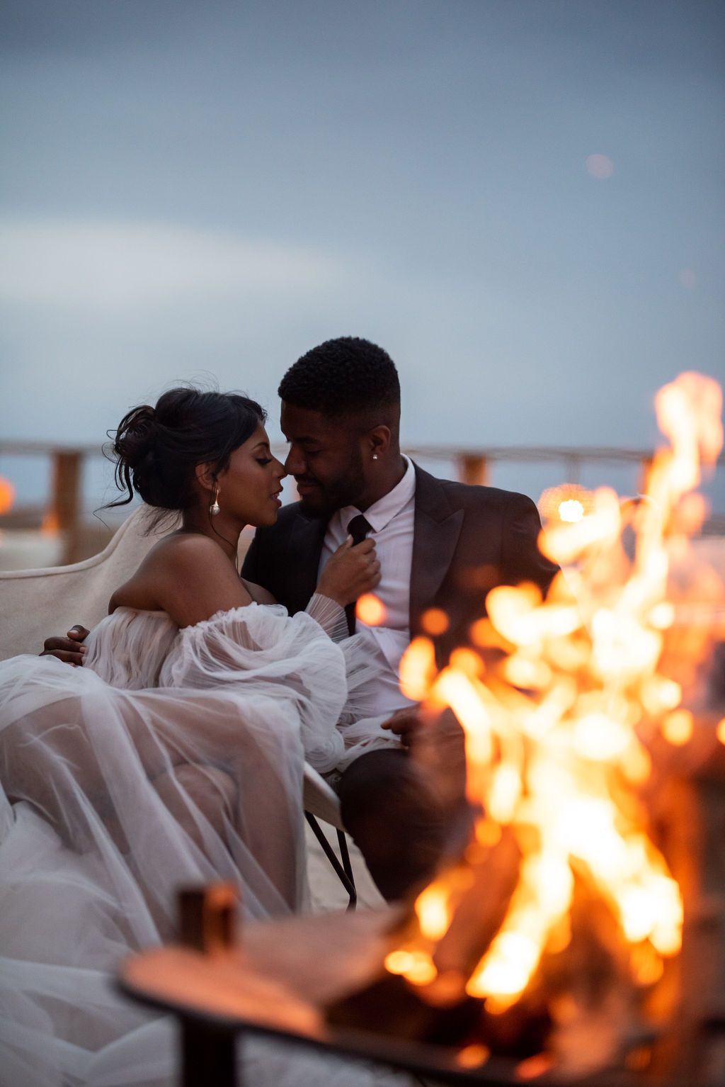 Bride and groom photographed by the fire during their elopement at Camp Alkamar in the Agafay Desert.
