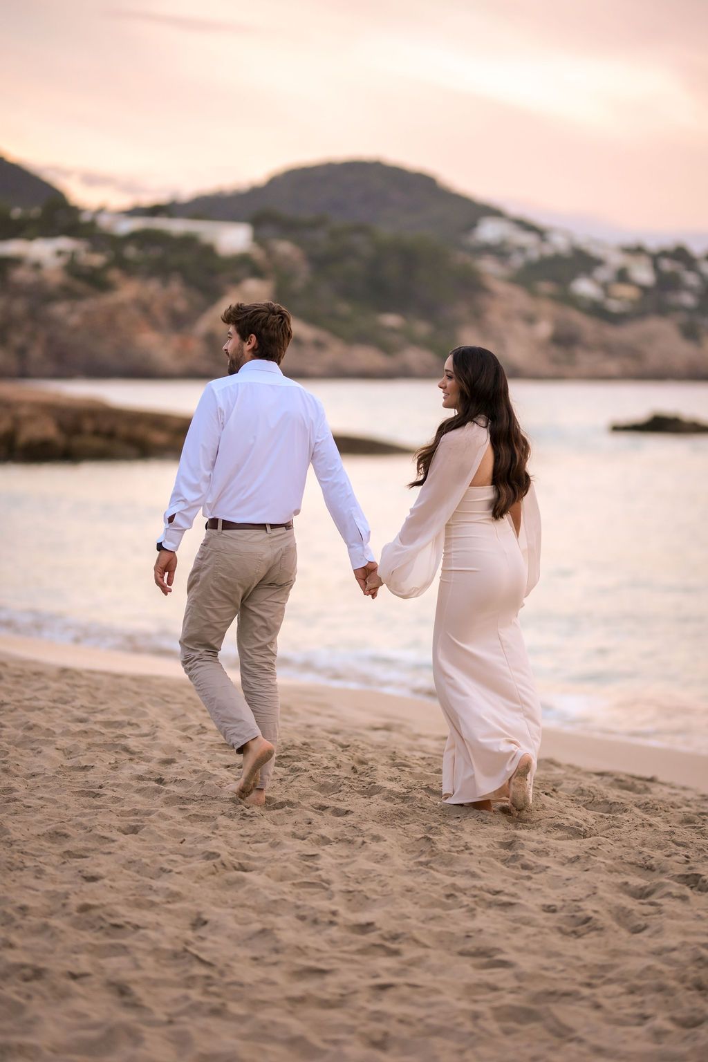 Couple holding hands walking on the beach in Cala Tarida