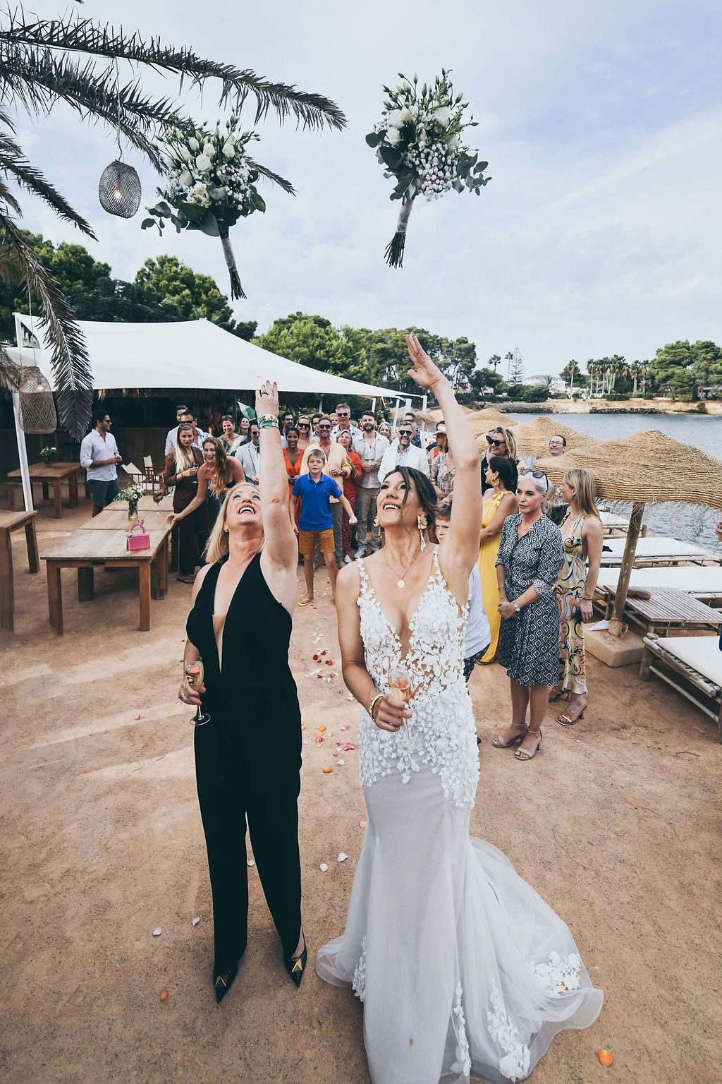 Bride and bride throwing the bouquet during their Babylon Beach Ibiza wedding.