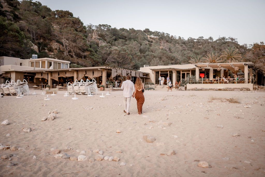 Couple walking to El Silencio after a sunset proposal photo session in Cala Molí, Ibiza