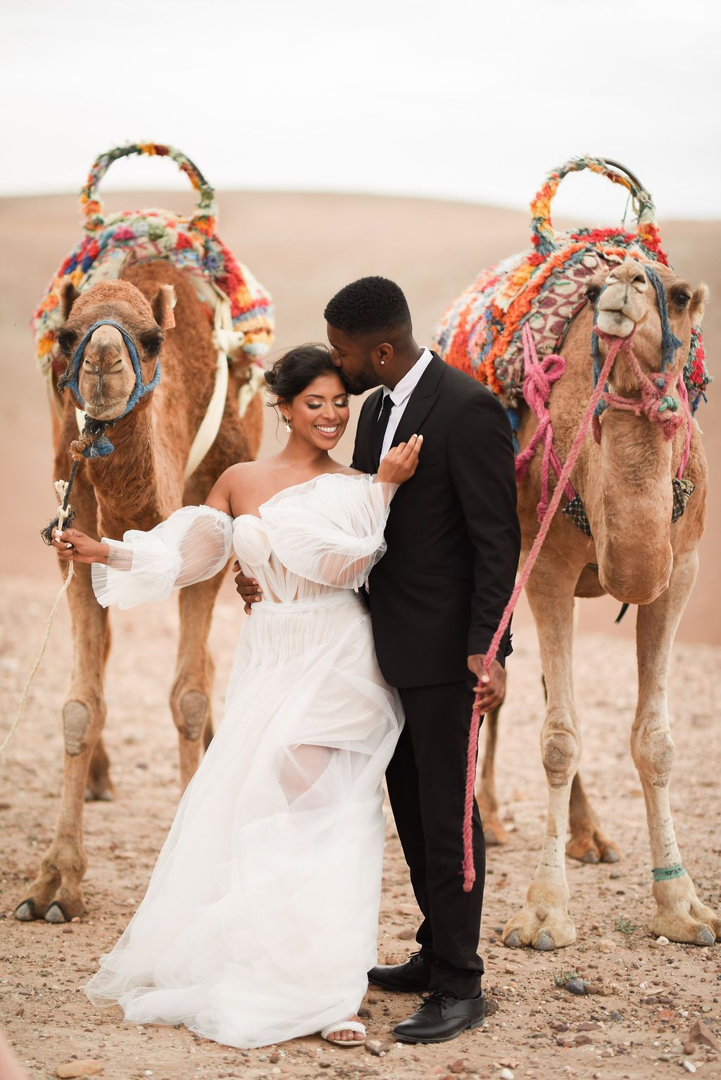 Bride and groom photographed with camels during their elopement in the Agafay Desert.