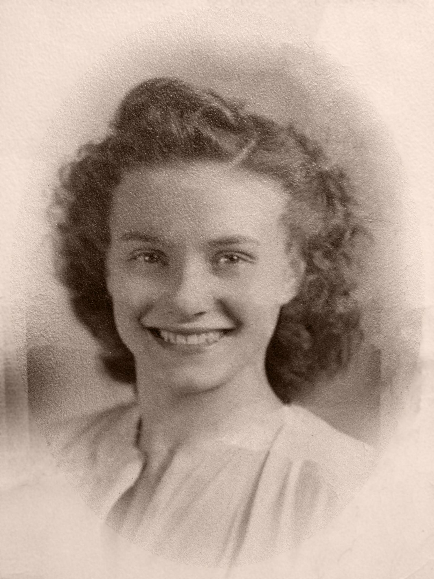 Vintage sepia portrait of a young smiling woman with curly hair, classic 1940s style photography.