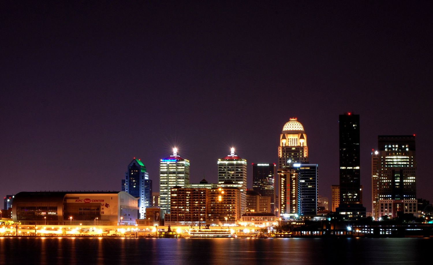 Louisville Kentucky city skyline illuminated at night reflecting over the Ohio River.