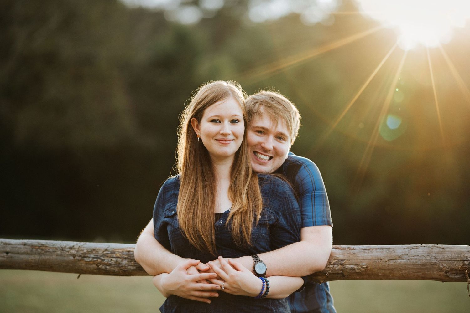 Young couple sitting together outdoors in a meadow during golden sunset with lens flare effect.