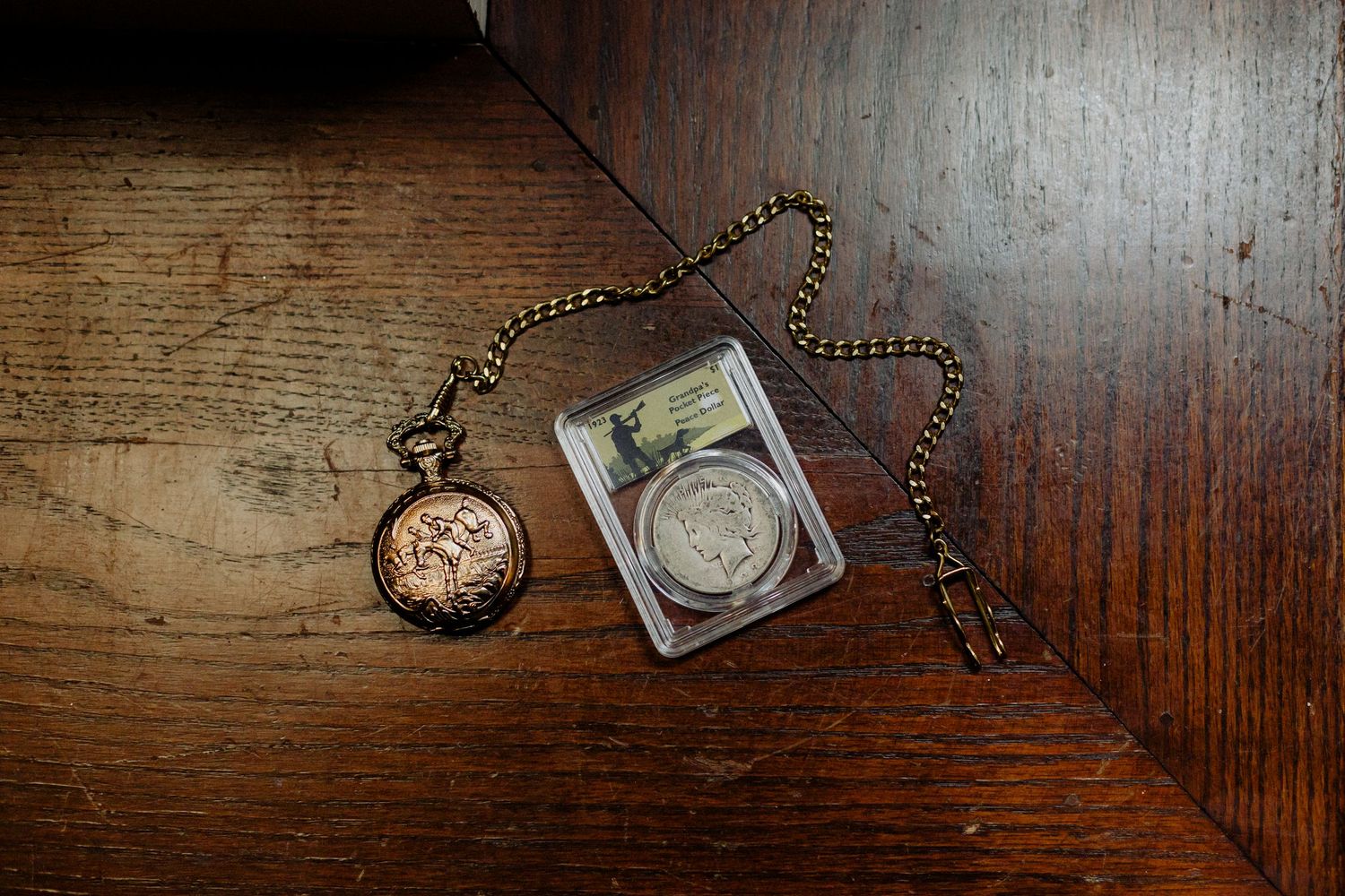 Vintage pocket watch and chain lying on a rustic wooden surface with dramatic lighting and shadows.