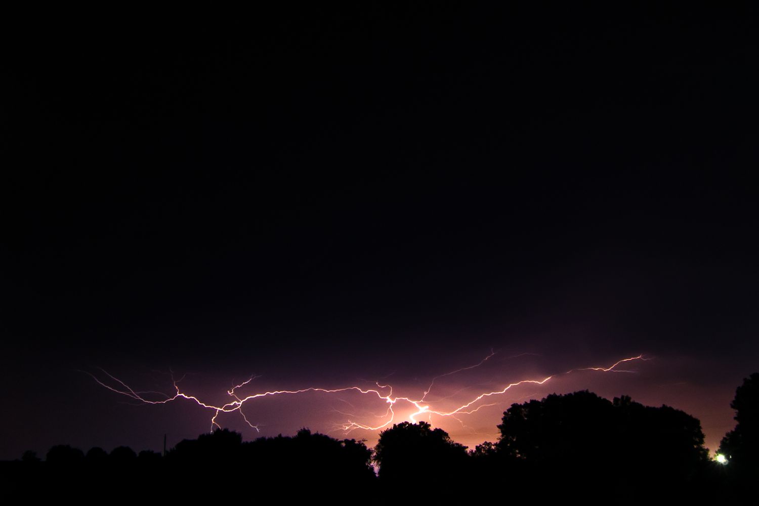 Multiple lightning bolts streak across a dark night sky in a dramatic display of natural electricity.
