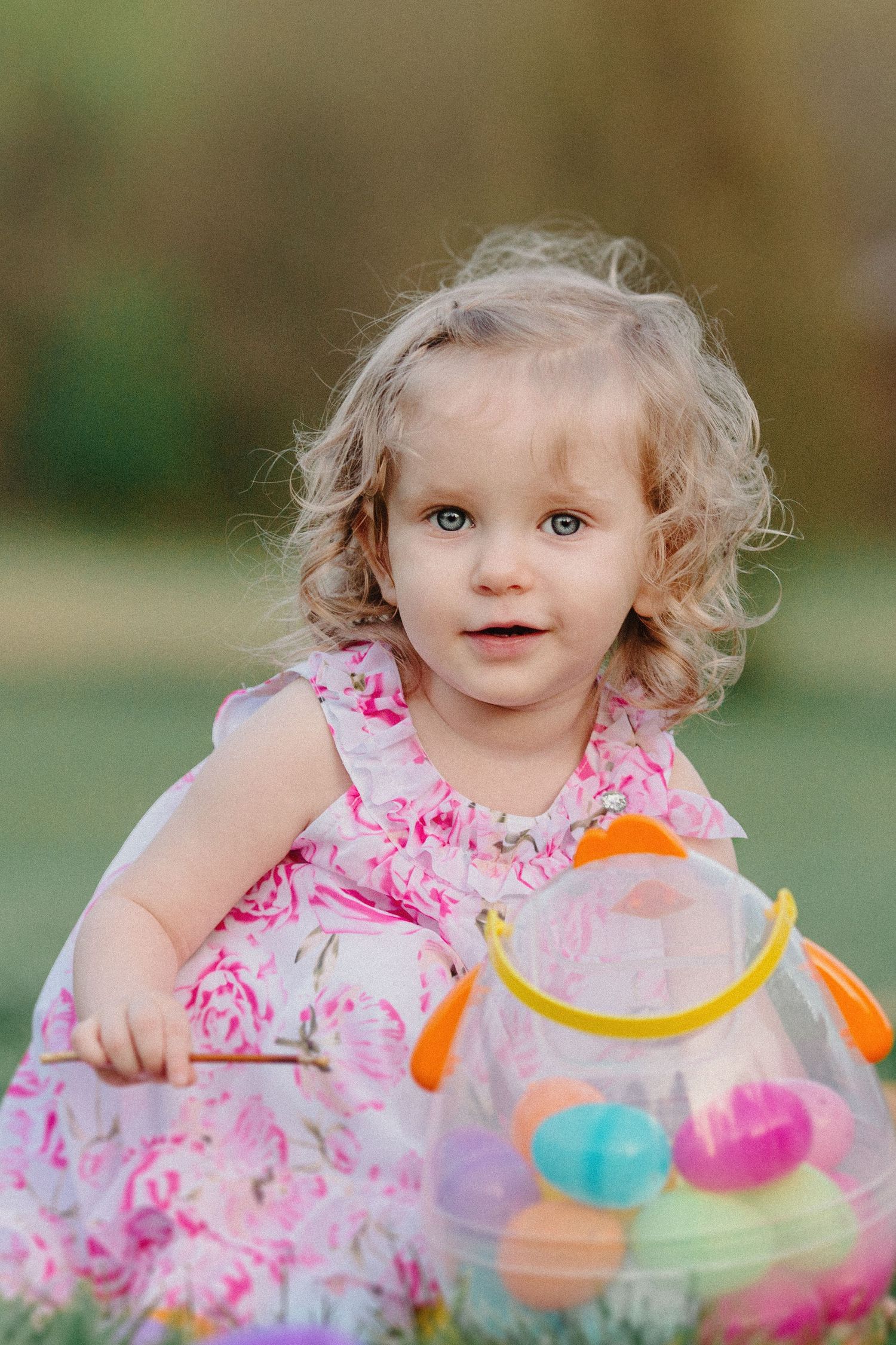A series of close-up shots showing a child in a pink floral dress playing with colorful plastic toys outdoors.