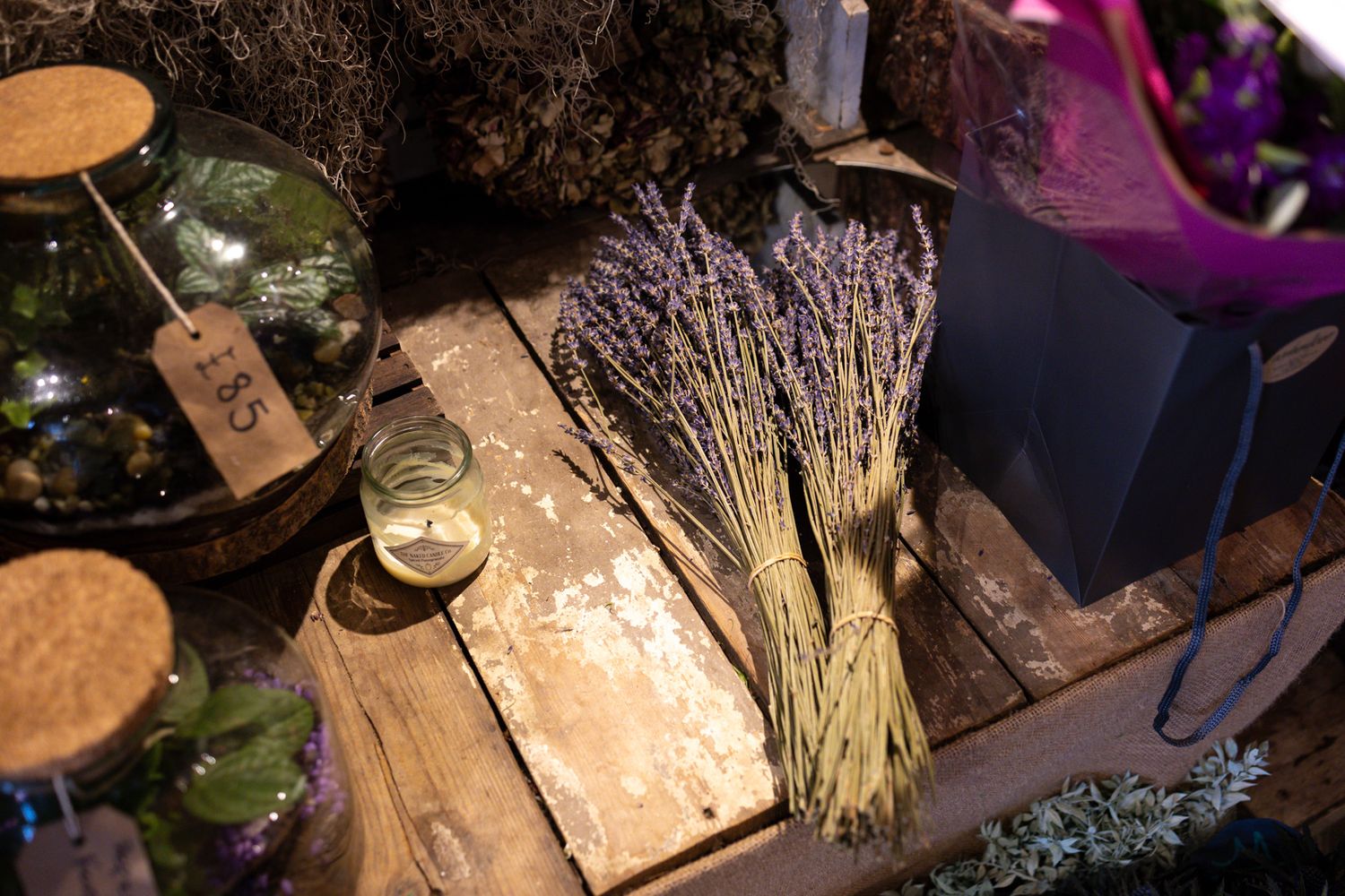 A rustic display of dried lavender bundles and glass jars on a weathered wooden surface with ambient lighting.