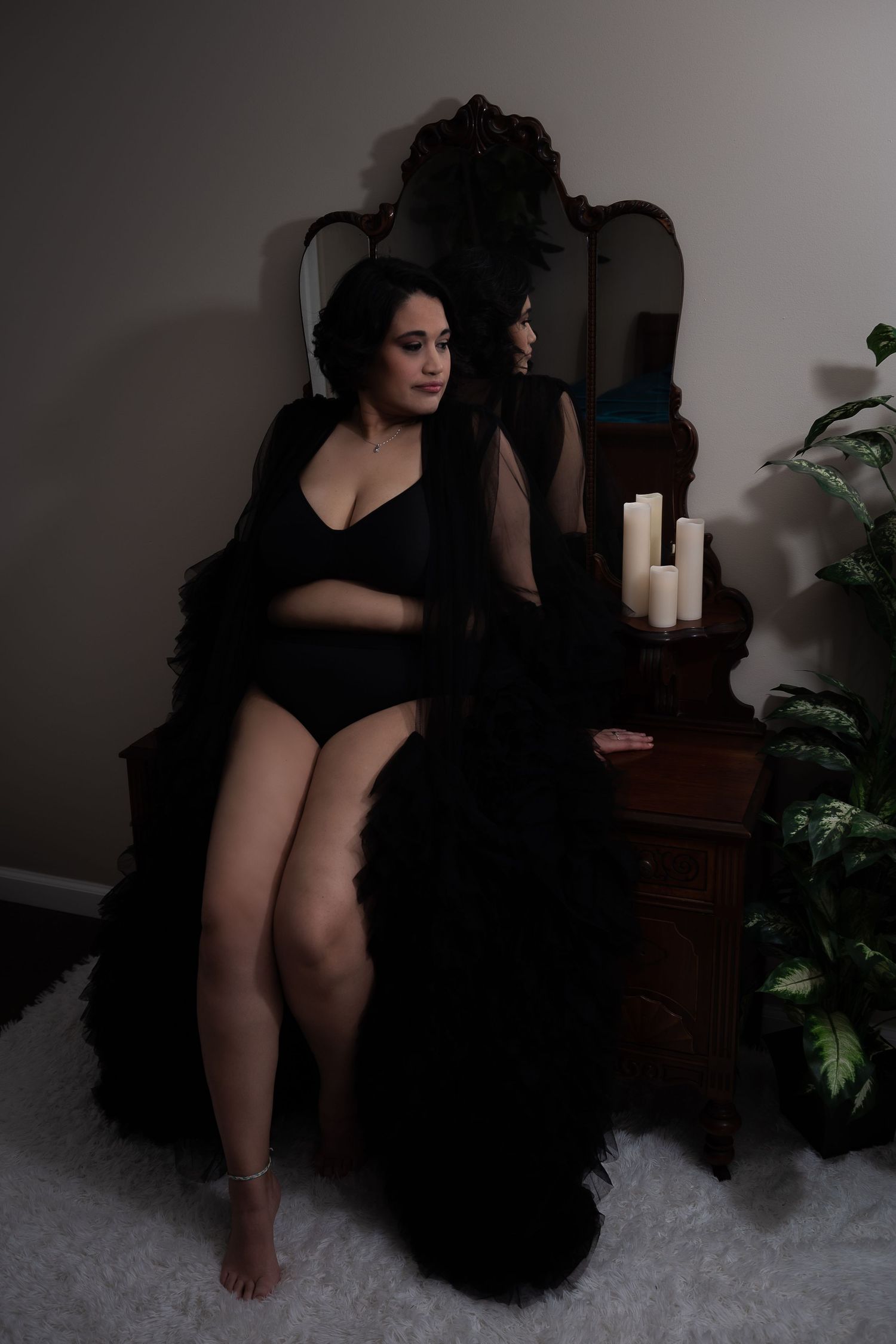 Moody boudoir scene with dark robe, lingerie and candles against vintage vanity in dim lighting.
