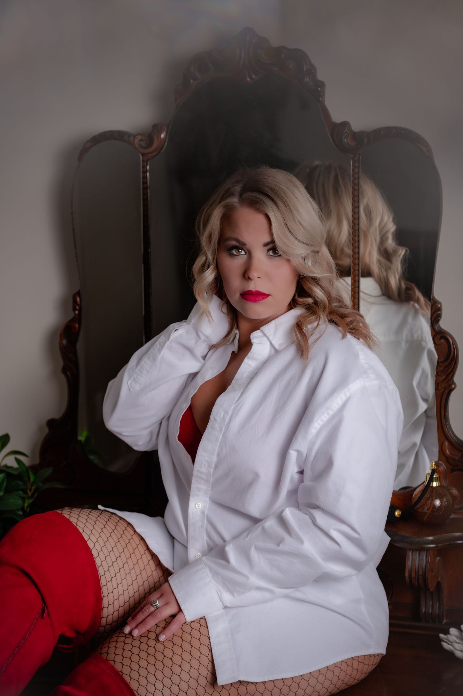 Boudoir photography featuring white button down shirt and red accents in moody lighting.