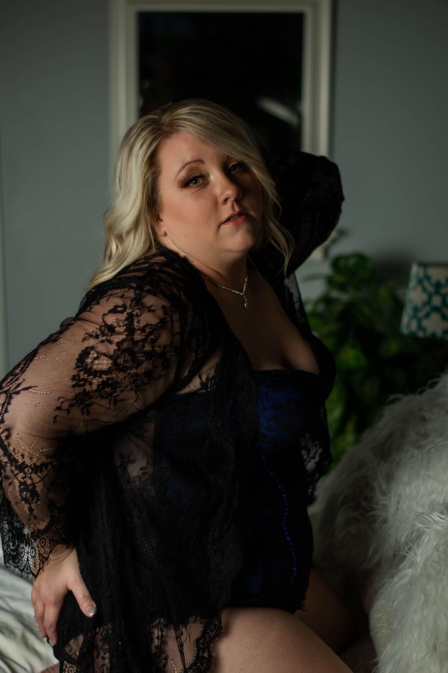 Dramatic boudoir portrait in black lace robe with moody lighting.