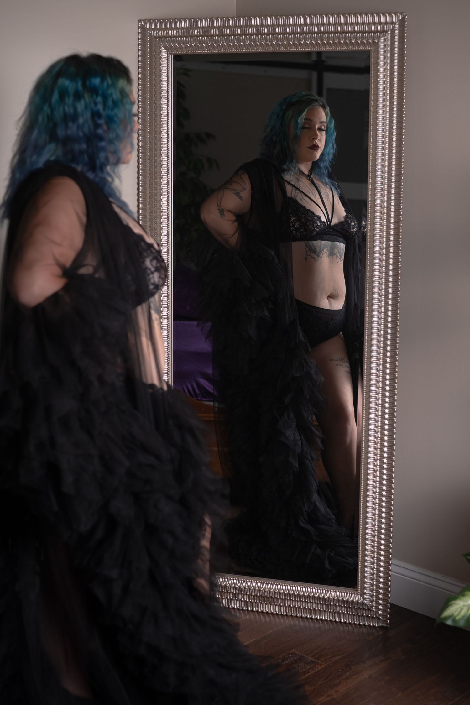 Artistic mirror reflection shot featuring black lingerie and teal hair.