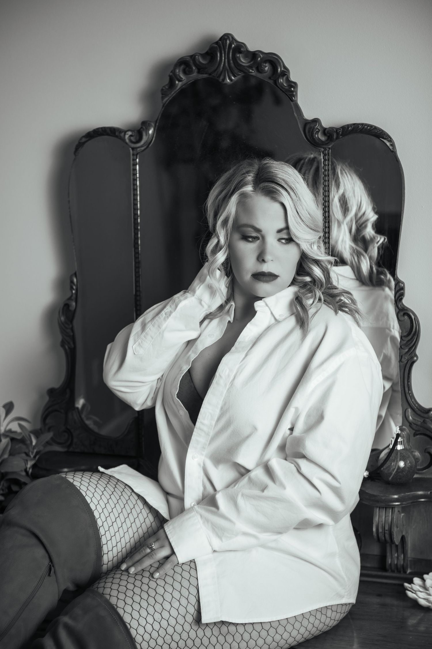 Black and white boudoir photo showcasing a white button-down shirt and fishnet stockings.