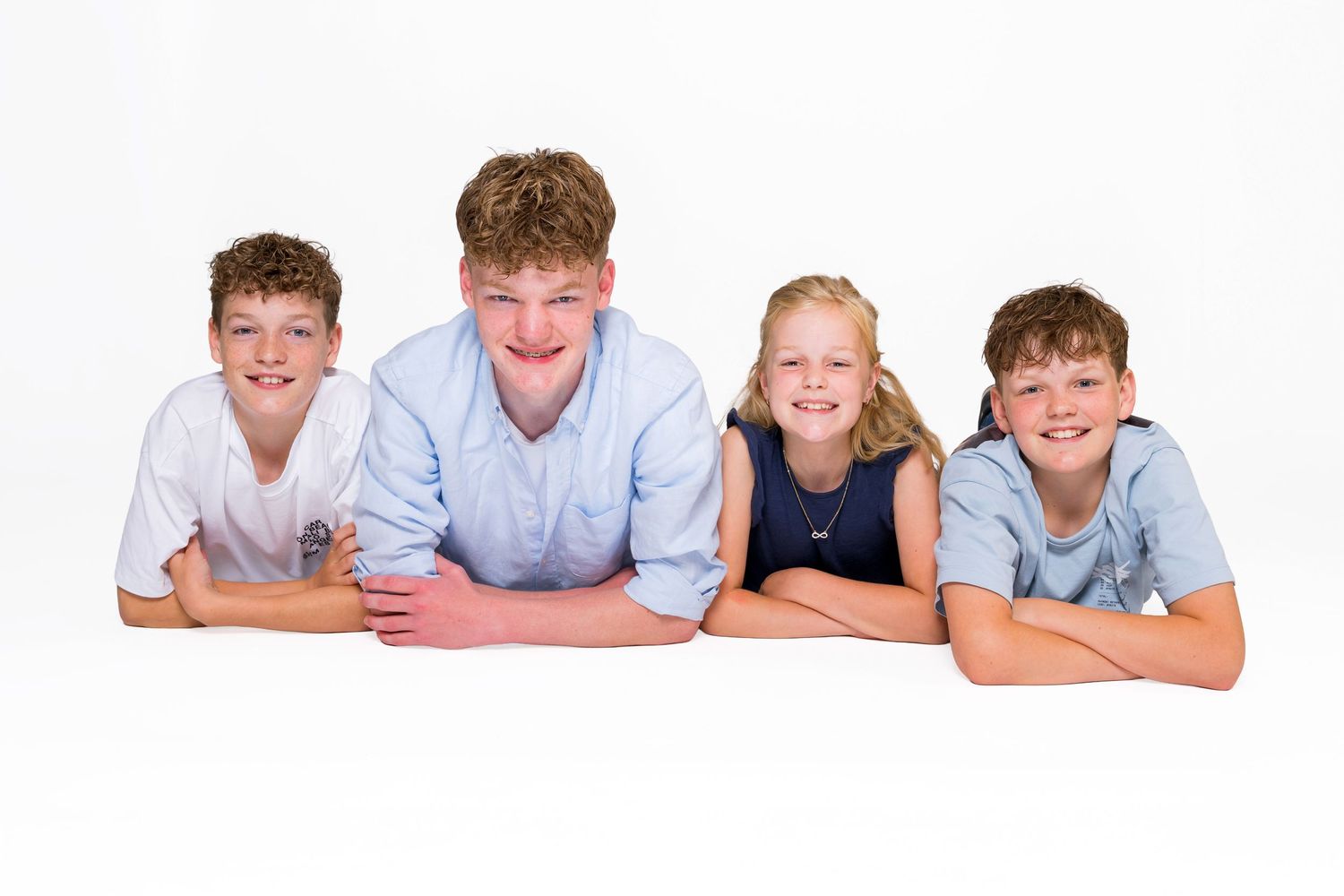 A horizontal row of smiling people lying down on a white background wearing light colored shirts.