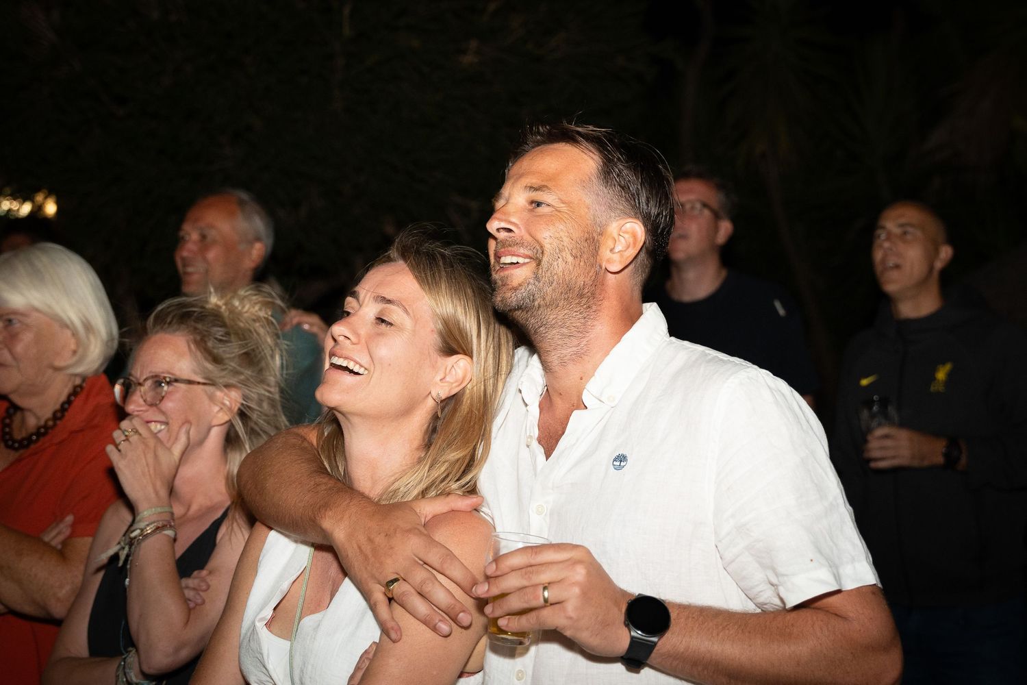 Crowd of people in a dark venue showing expressions of joy and excitement during an event.
