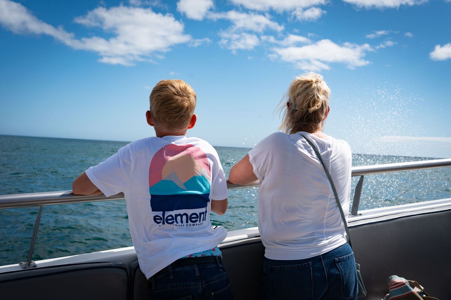 People enjoying a boat ride on a sunny day with blue skies and ocean views.