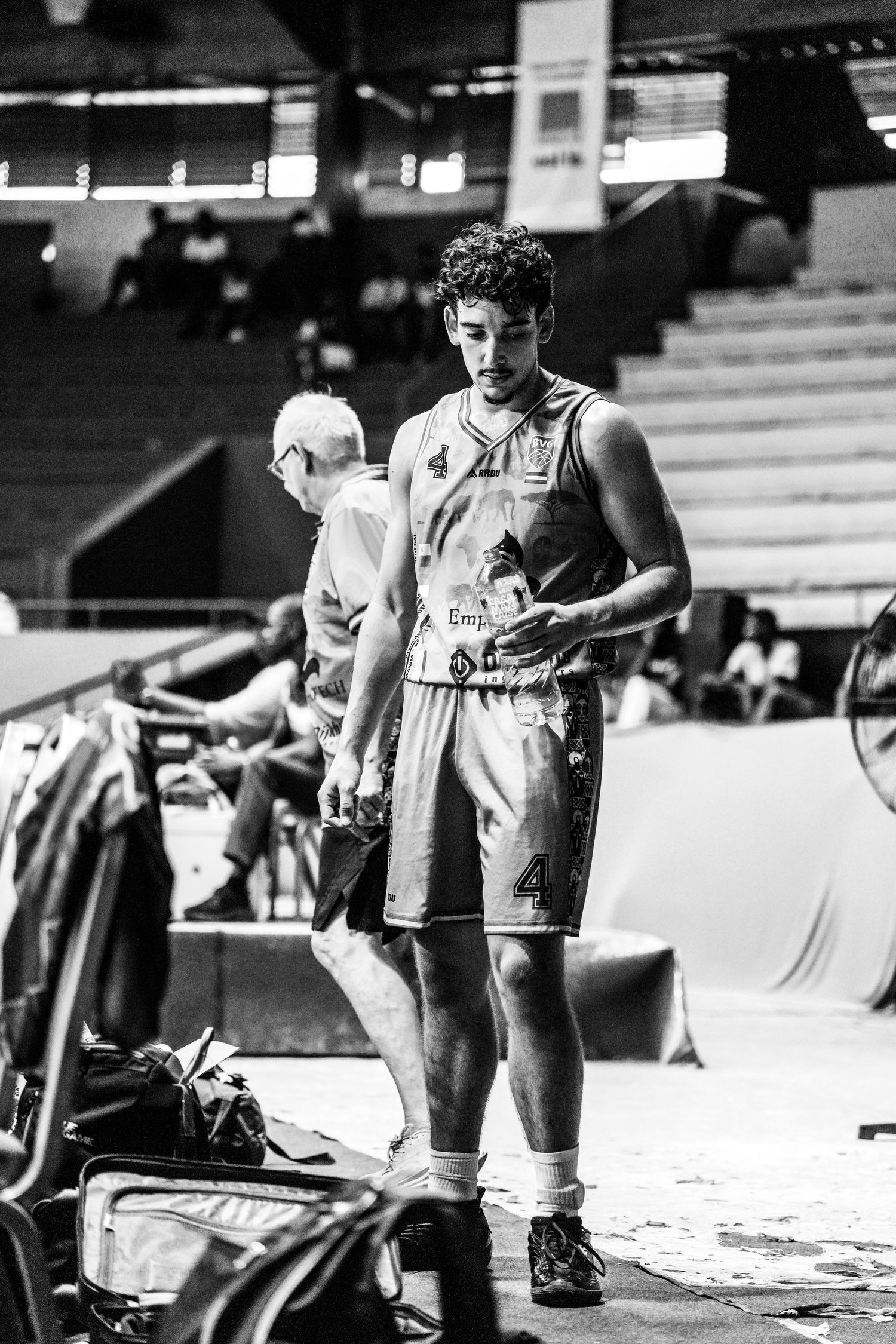 Black and white photo of a young basketball player wearing jersey number 4 standing in an indoor arena.