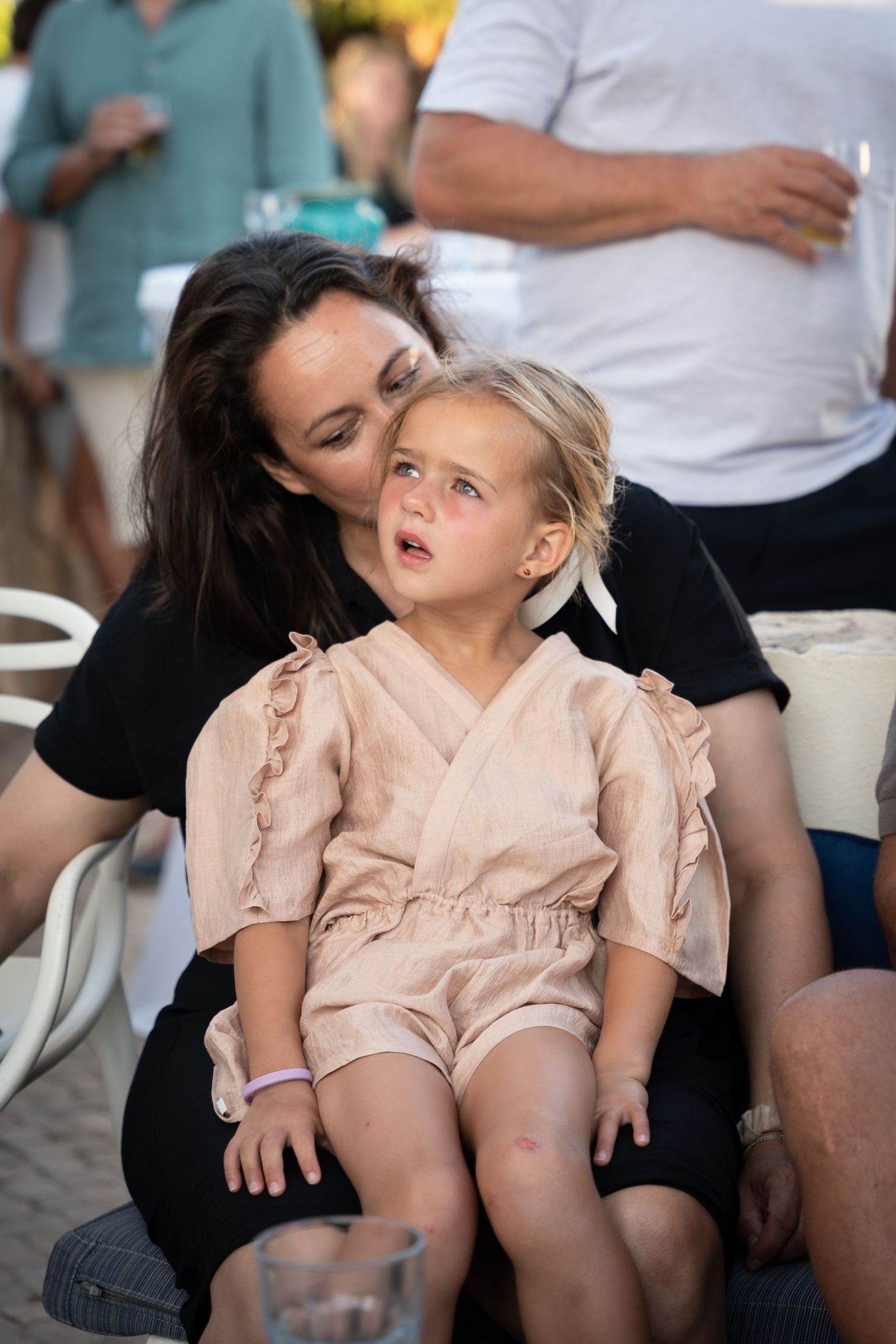 Series of photos showing a child in a peach-colored dress resting on someone's lap in various playful poses.