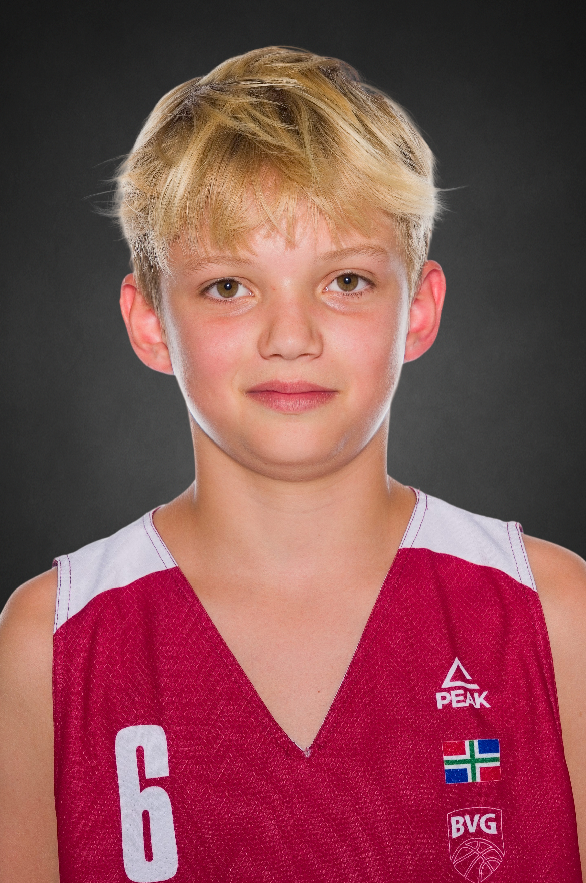 Young basketball player with blond hair wearing a red number 6 Peak jersey with BVG logo against a dark gray studio background.