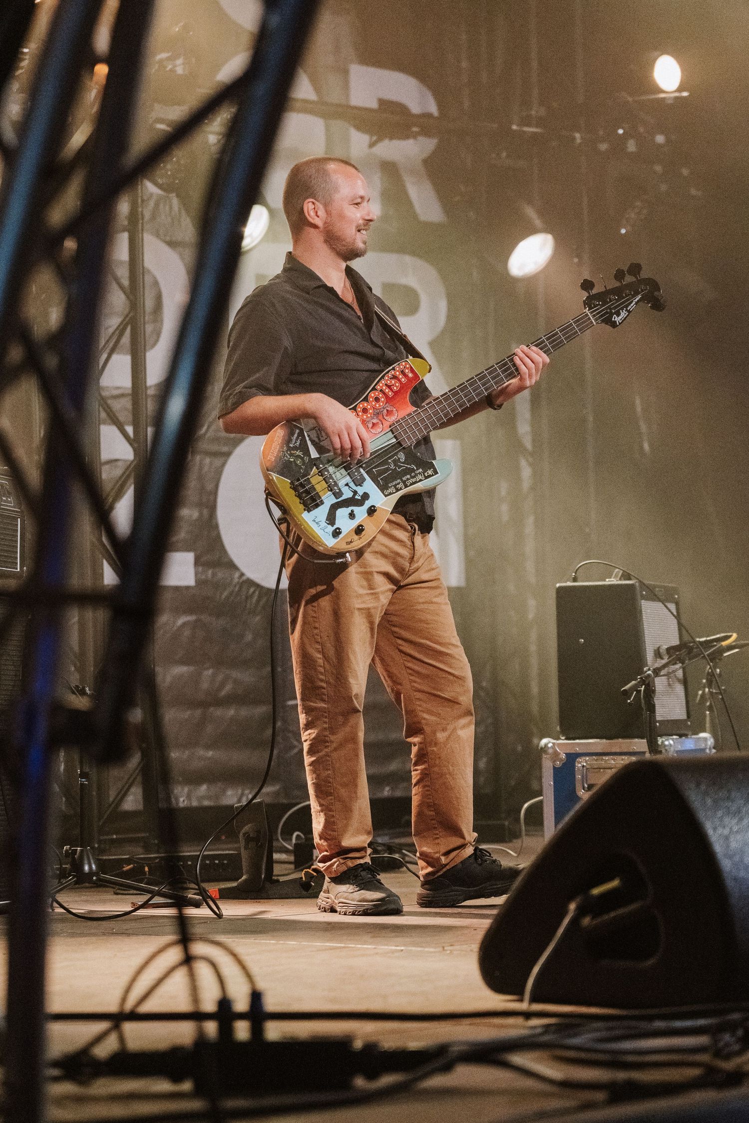 Panoramic series of three shots showing a guitarist playing on stage wearing brown pants in moody atmospheric lighting.