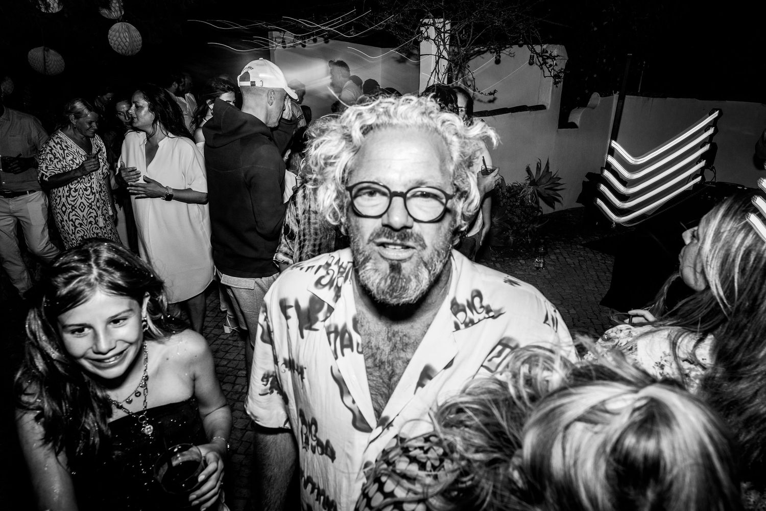 A black and white photo showing a lively party scene with people in a crowded room.
