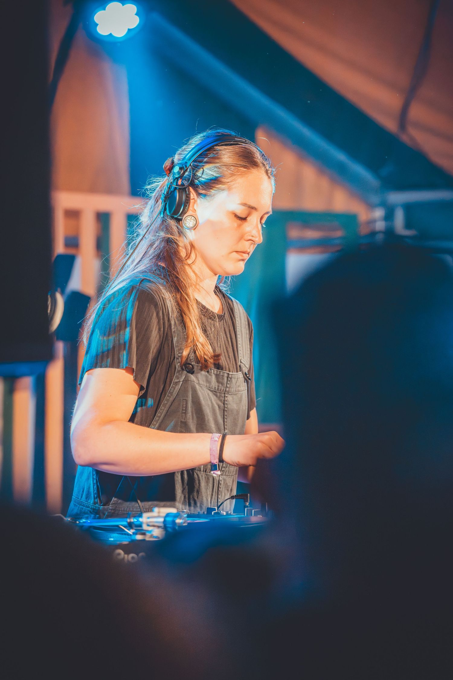 DJ performs at a nightclub with dramatic blue lighting while mixing tracks on professional equipment.