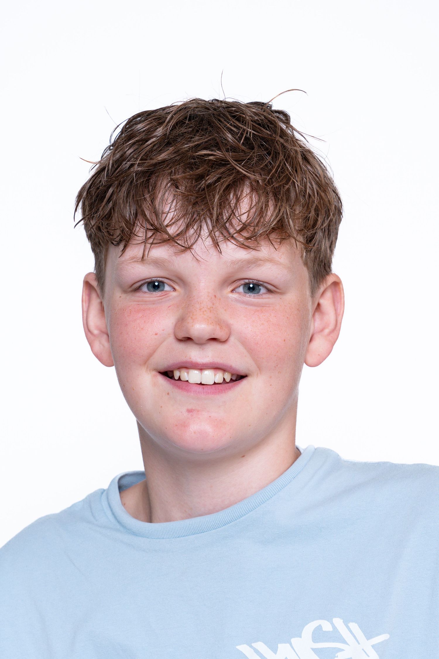 Young person wearing a light blue t-shirt smiles warmly against a white background.