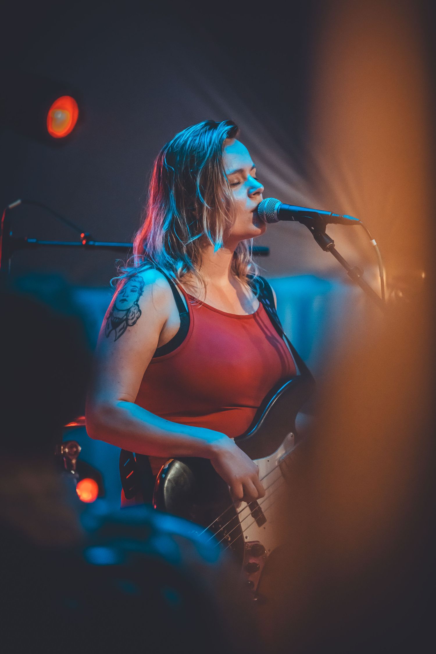 Energetic singer performing under dramatic blue and red stage lighting during a live music concert.