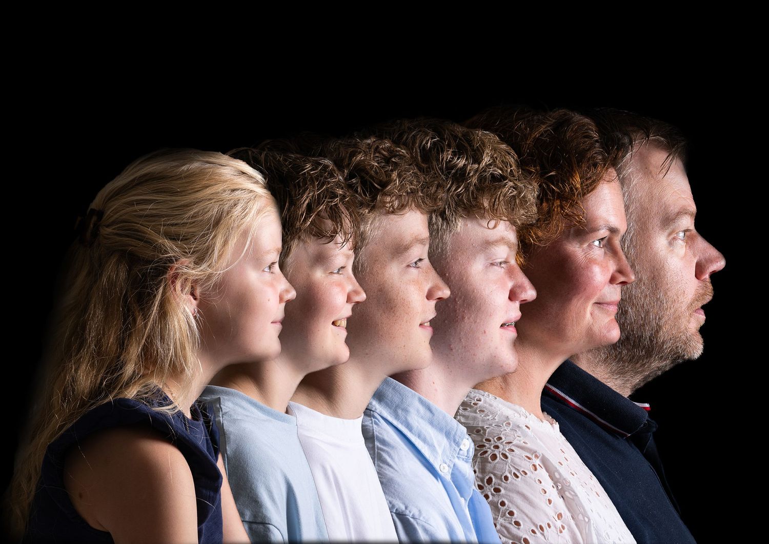 Side profile portrait of a line of six people against black background showing age progression order.
