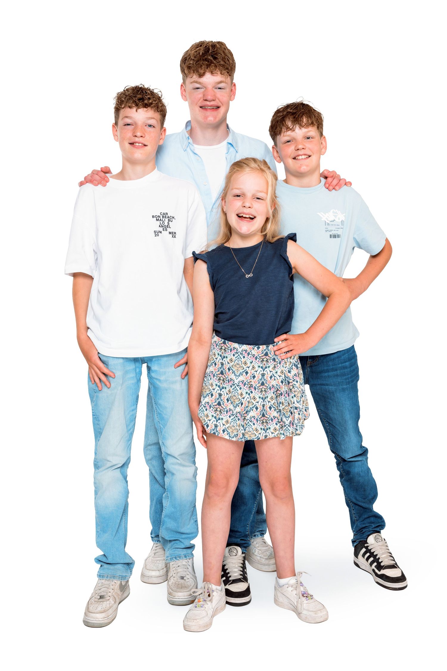 Happy children standing in casual clothing with blue jeans, white shirts and sneakers showing their lower bodies.