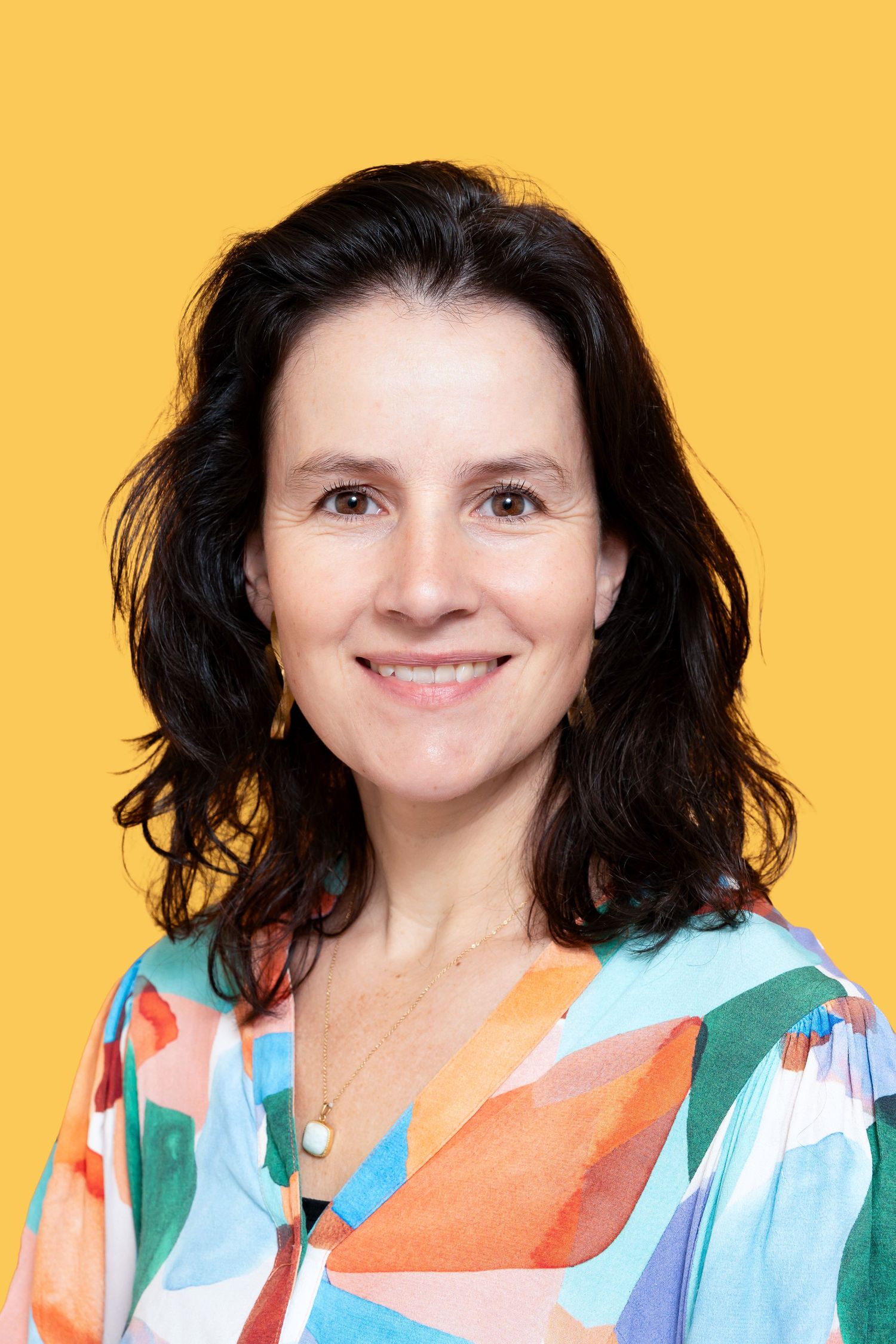 A series of five headshots showing someone wearing a colorful patterned top against a yellow background.