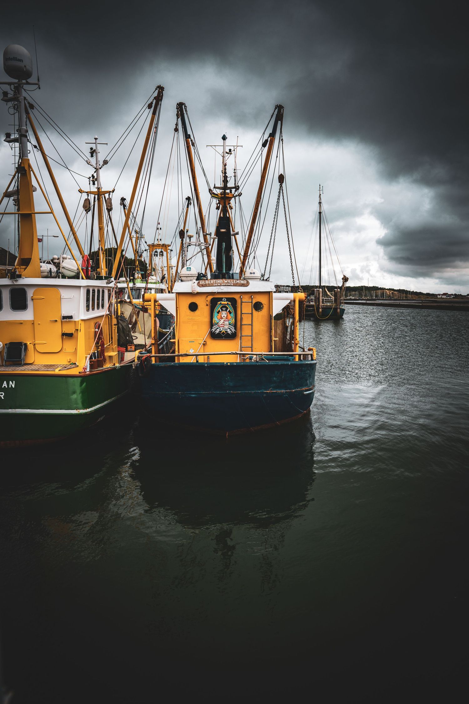 Orange fishing boats docked under dramatic stormy sky.
