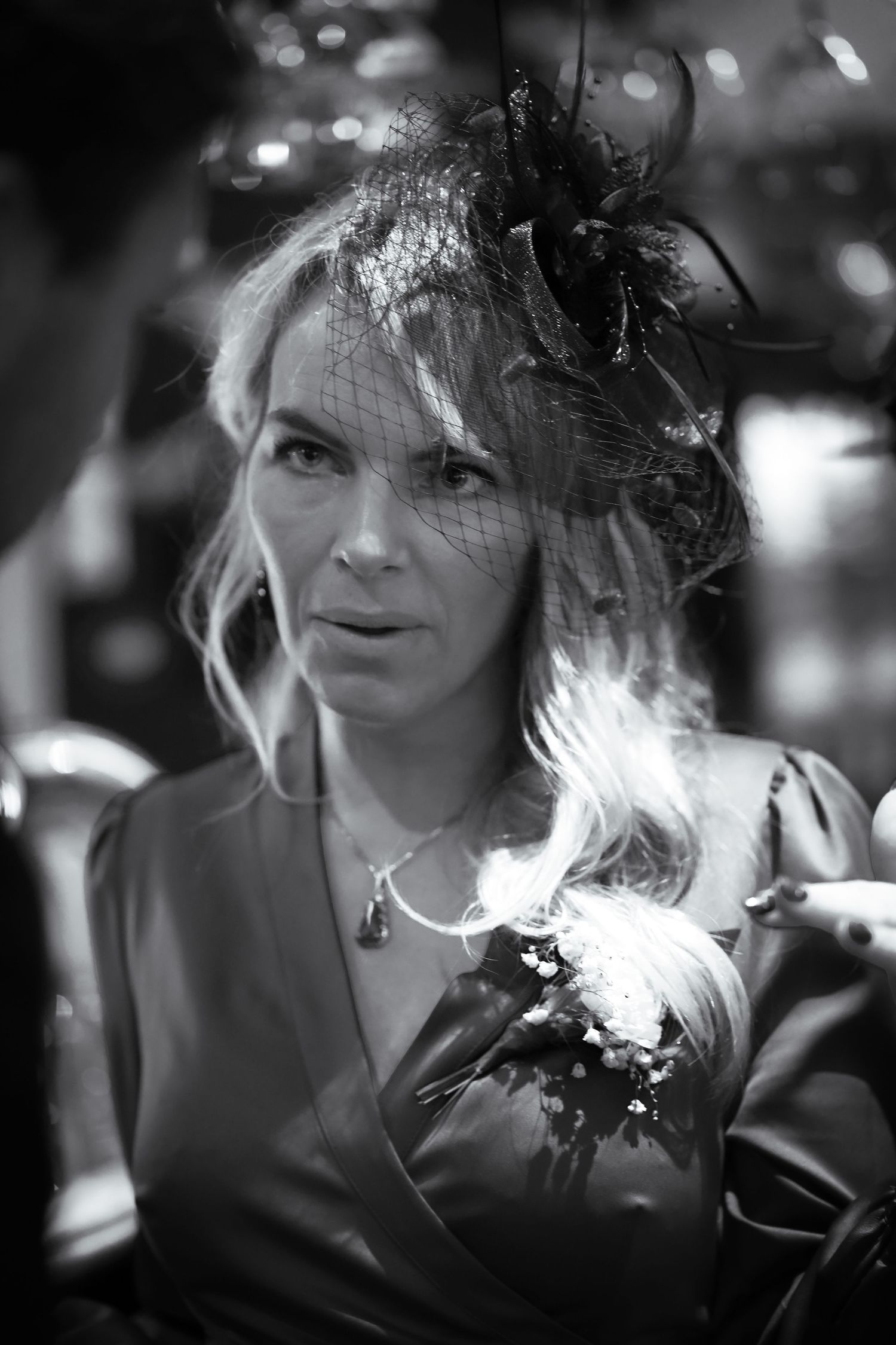 A black and white portrait showing an elegant fascinator headpiece adorned with feathers and decorative elements.