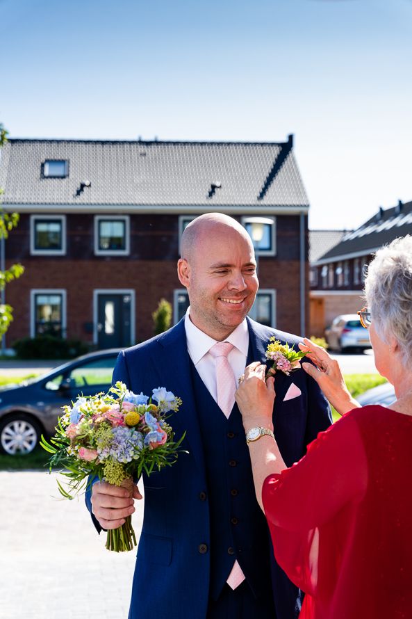 Wedding guests sharing a joyful moment outdoors with colorful bouquet and formal attire.