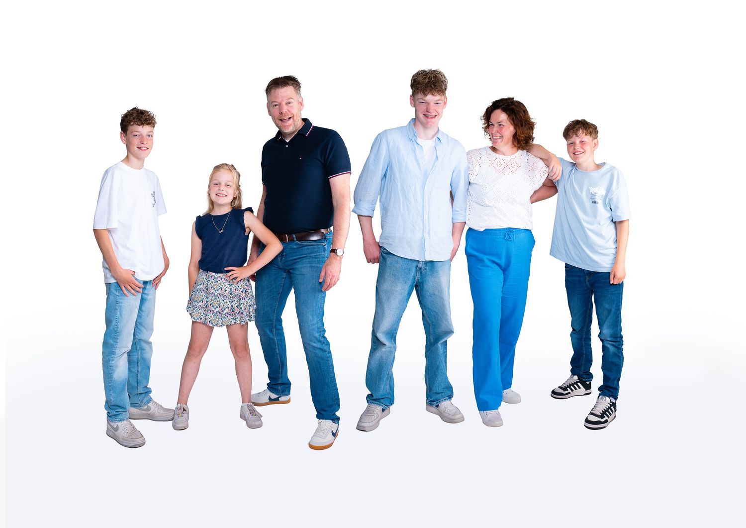 A family of six people wearing casual clothing poses together against a white studio background.