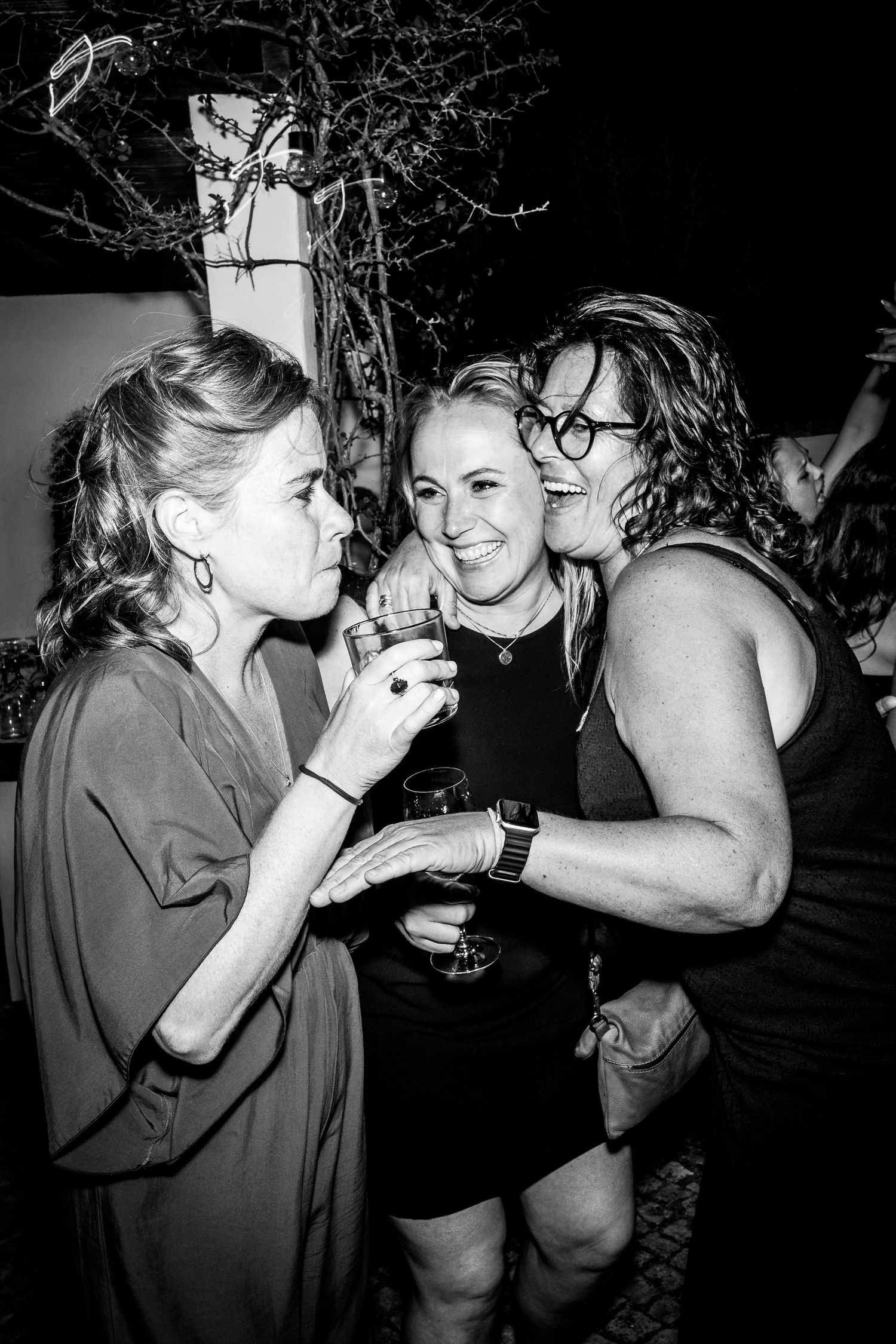 A black and white series of candid party photos showing friends laughing and having drinks together at night.