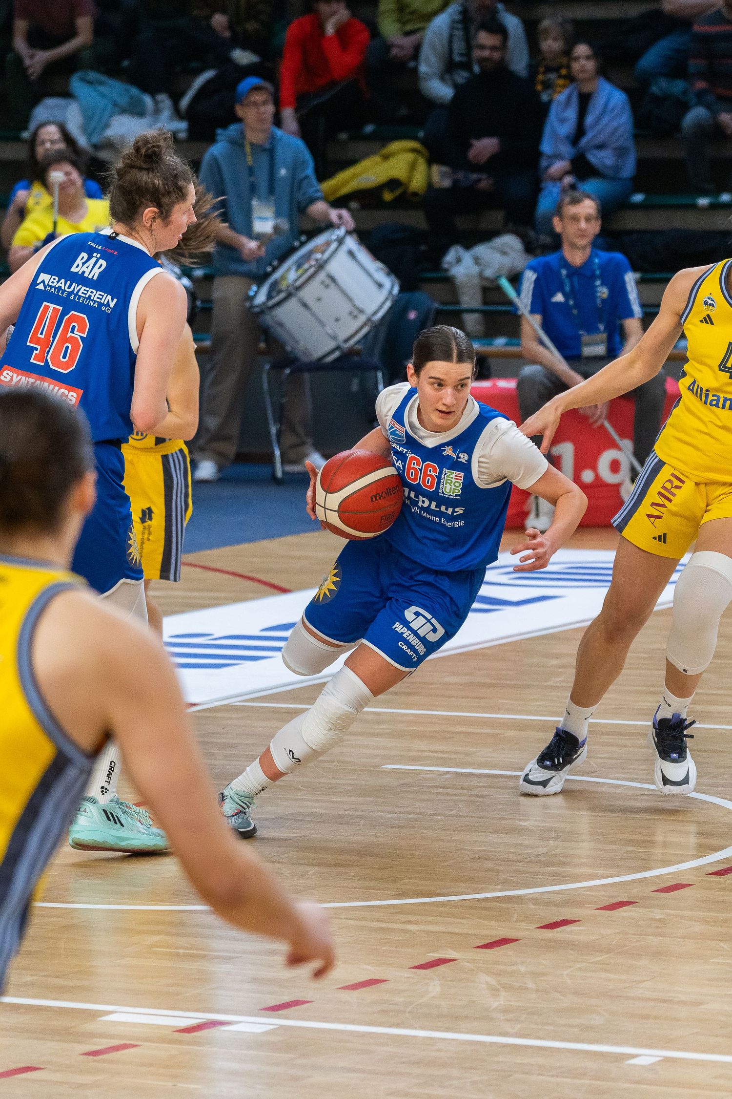Basketball players dive for a loose ball during an intense game on the hardwood court.