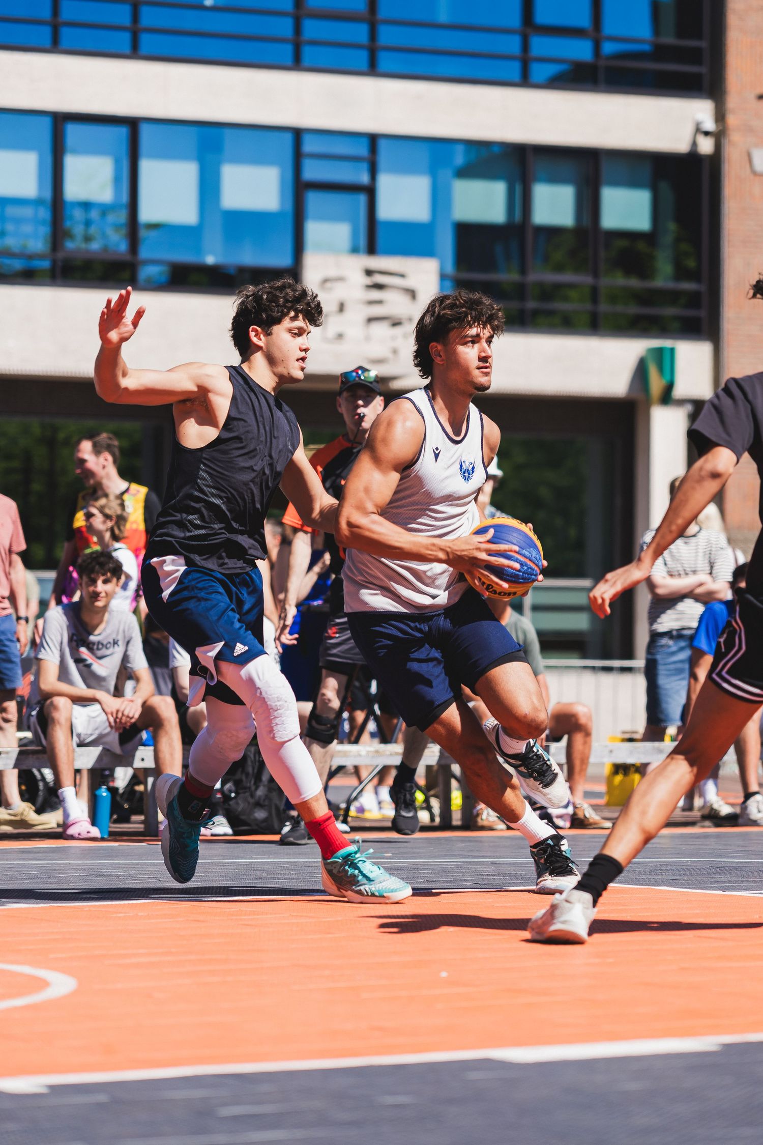 Young basketball player drives to the basket while being defended during an outdoor urban 3x3 tournament.