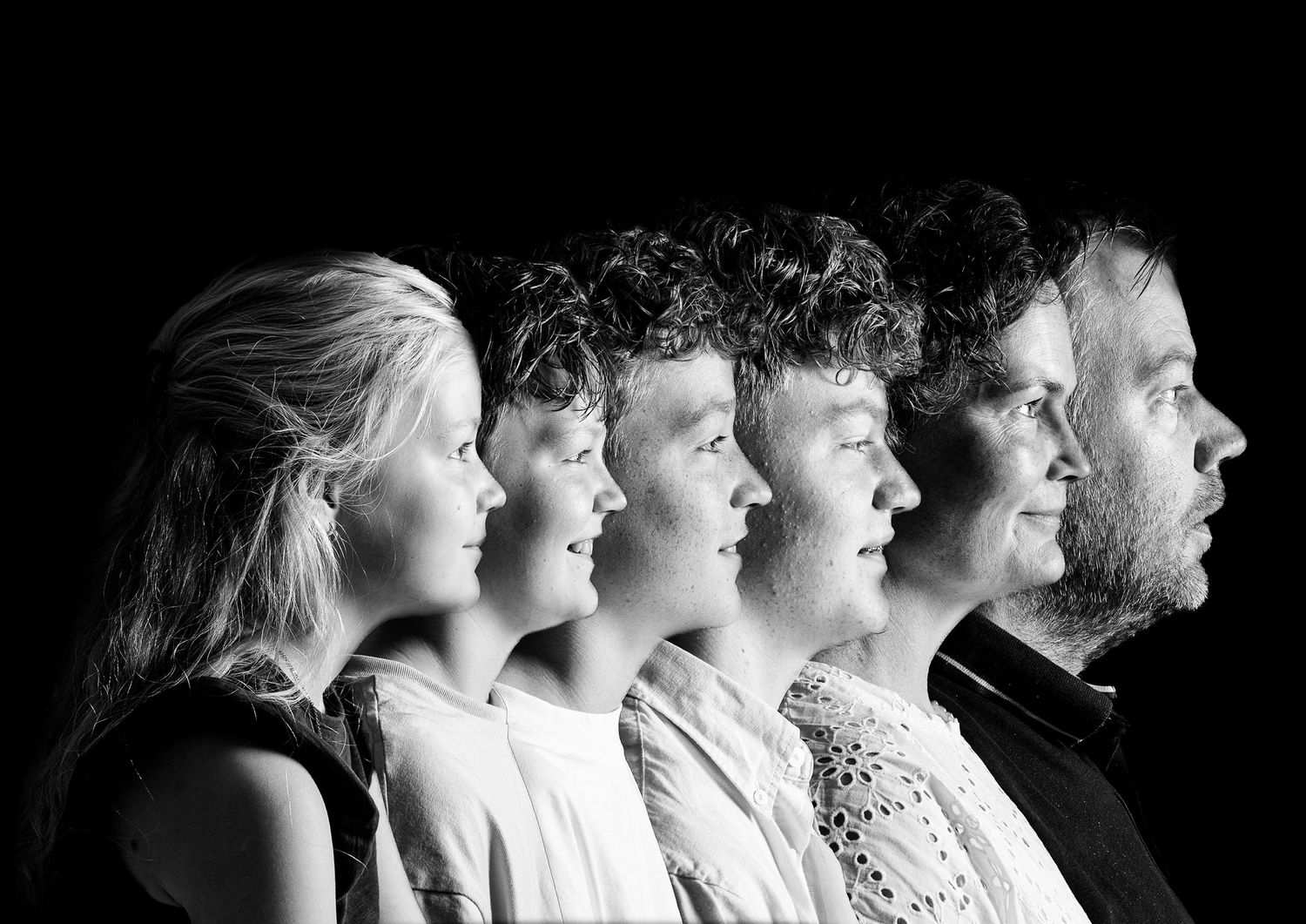 Black and white profile portrait showing six people lined up in descending height order from right to left.