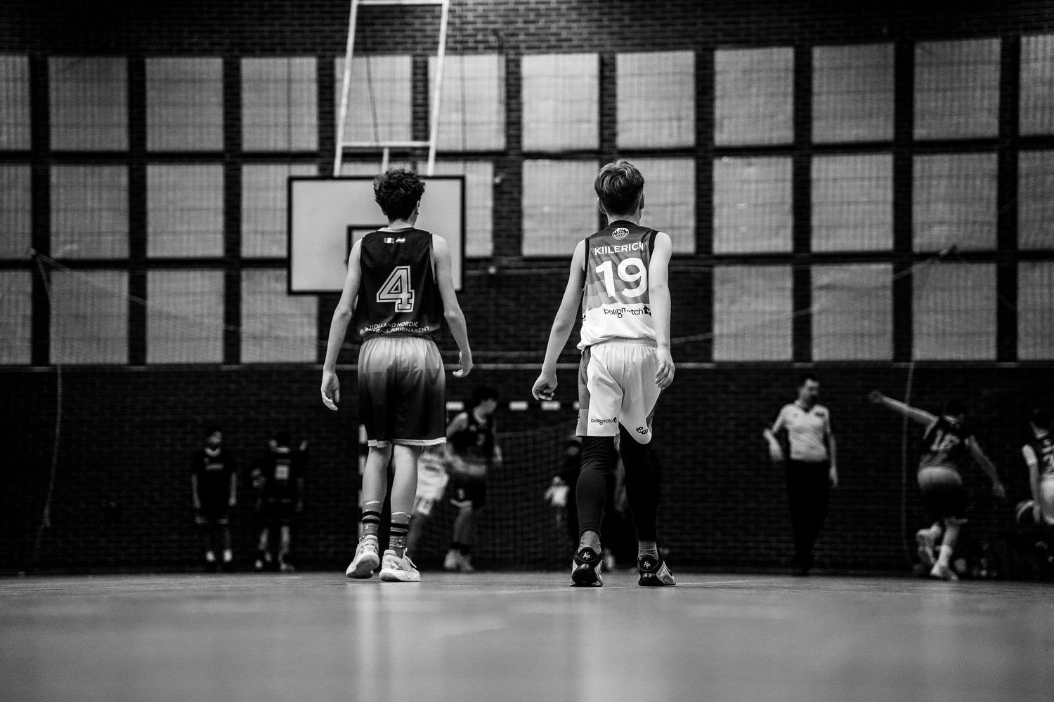 Two basketball players, wearing jerseys 4 and 19, face off on an indoor court in a black and white photo.