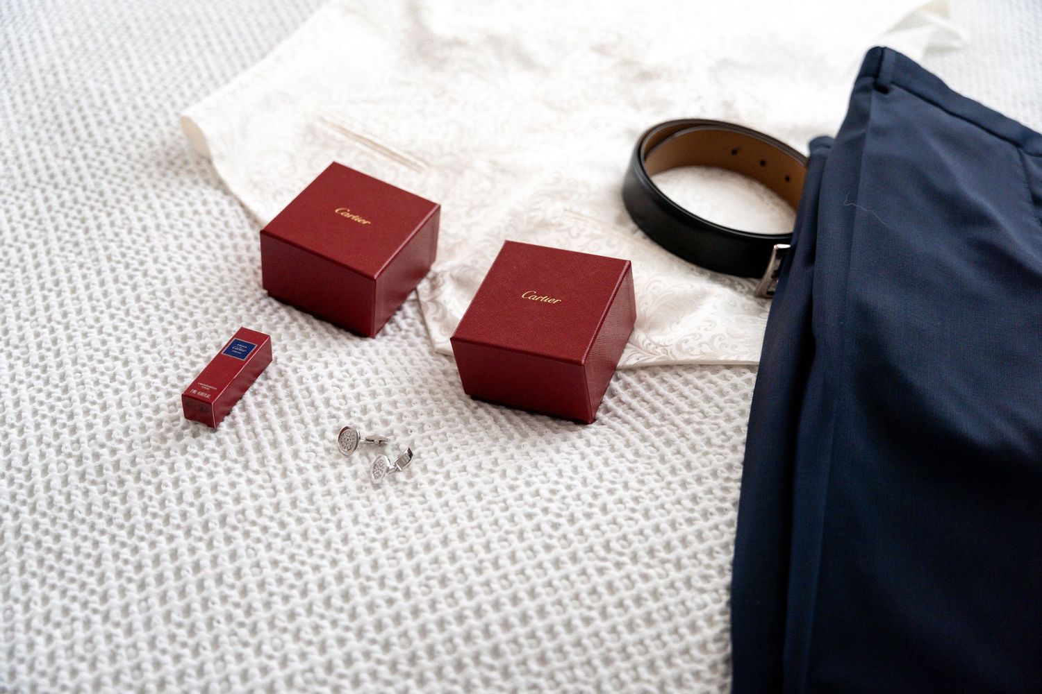 Small red jewelry boxes scattered on a white textured surface next to dark blue fabric.