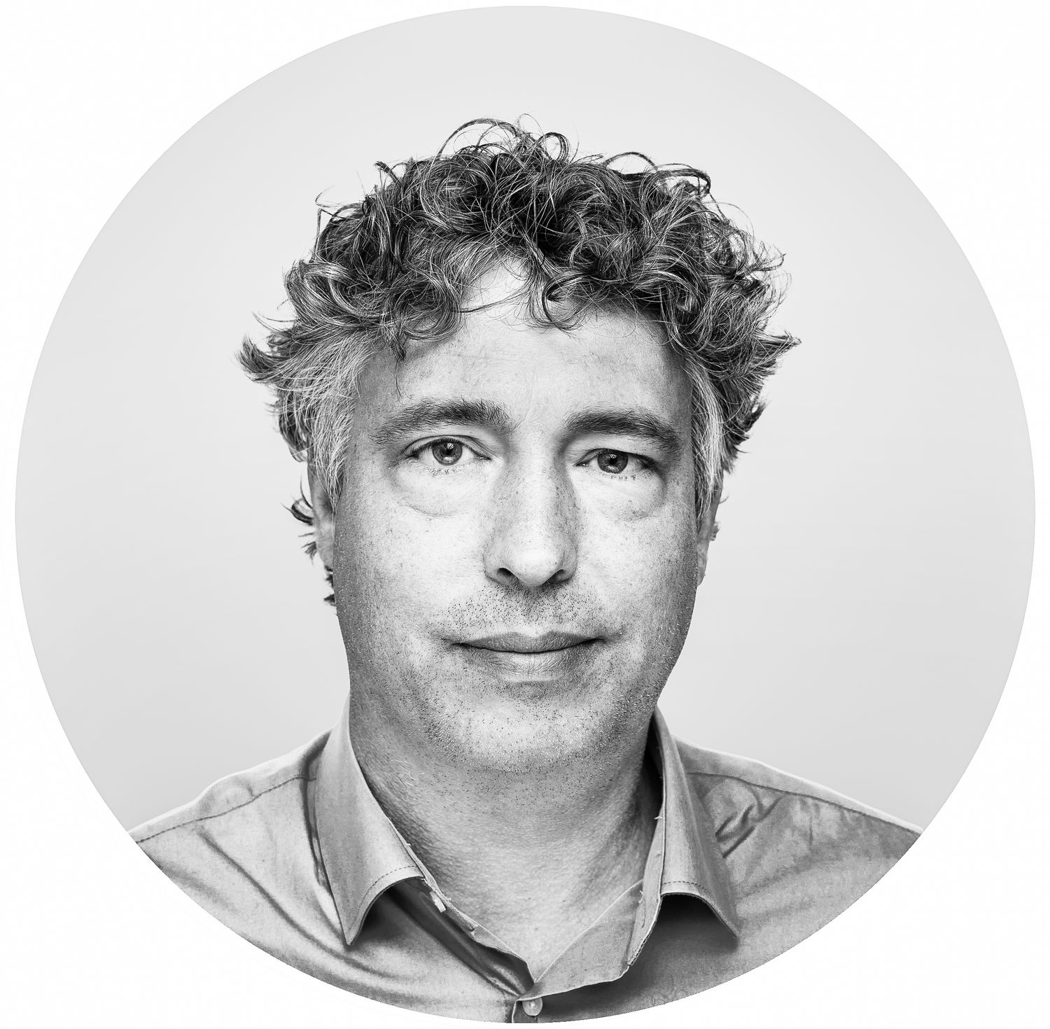 Black and white portrait of a person with curly hair and a button-up shirt against a light background.