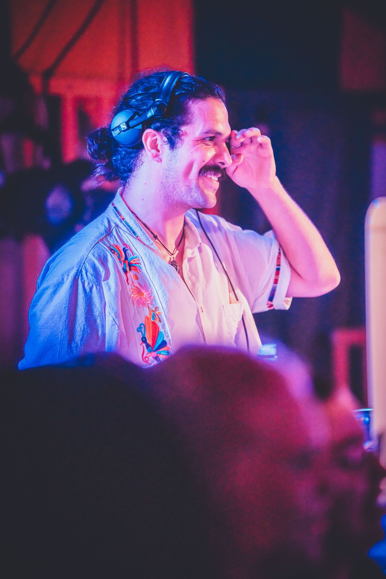 A performer smiles on stage bathed in blue and red lighting during a live music performance.