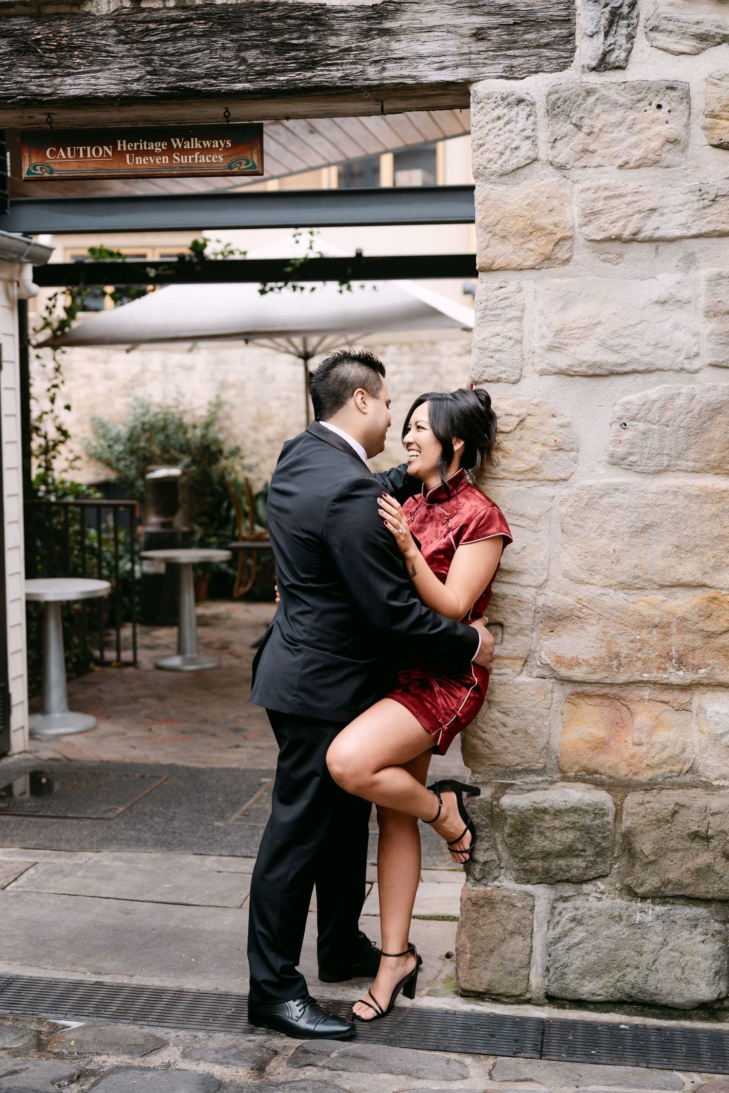 Pre-Wedding photos of couple embracing against stone wall at The Rocks Sydney heritage precinct.