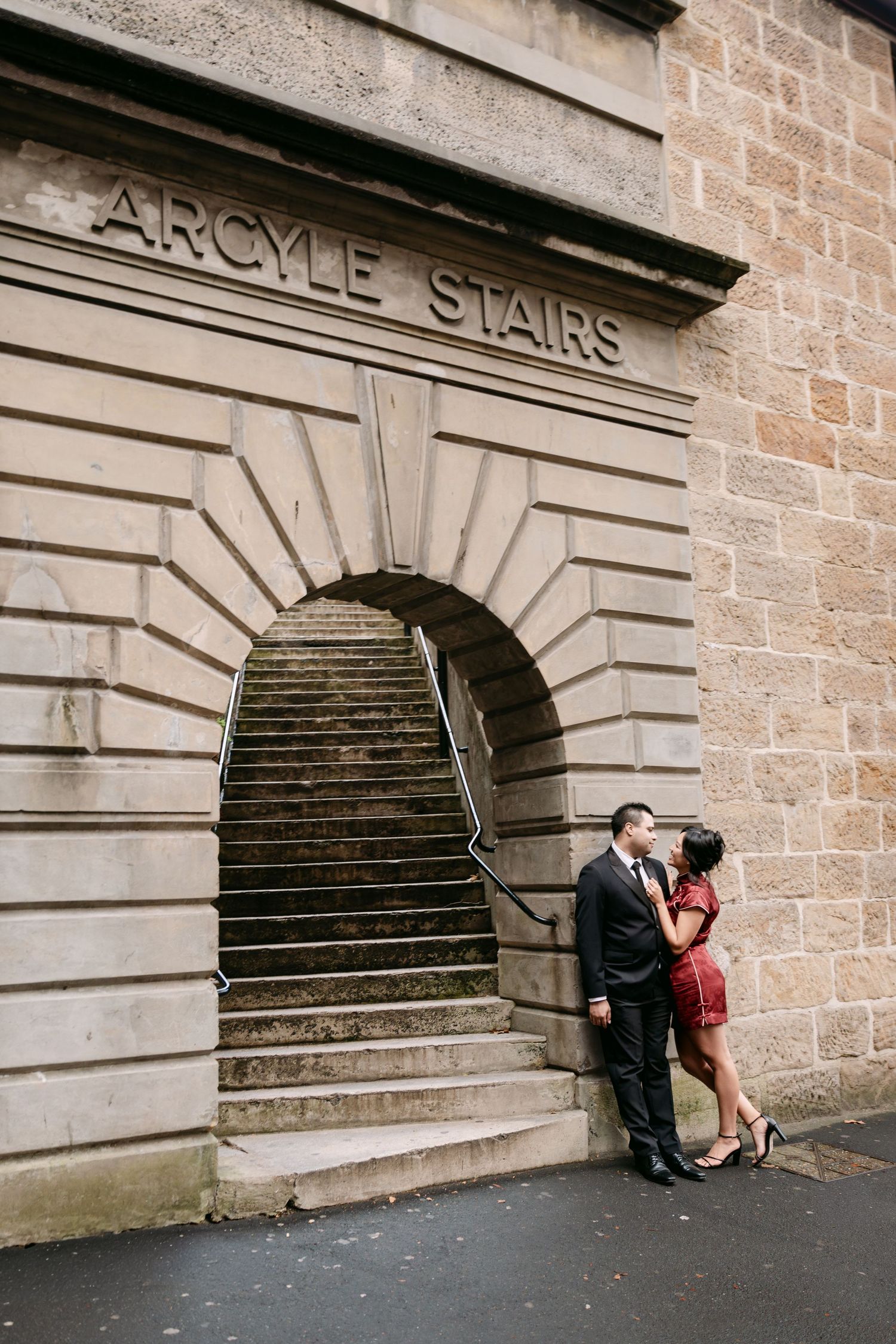 Pre-Wedding photos of Couple kissing beside historic Argyle Stairs sandstone archway in The Rocks Sydney.