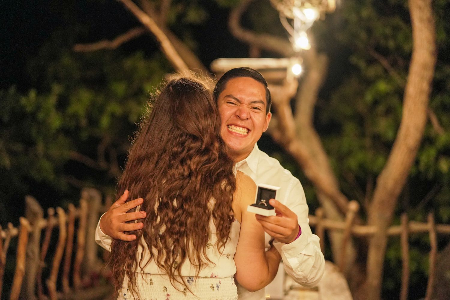 A joyful moment captured under twinkling lights in an outdoor garden setting.