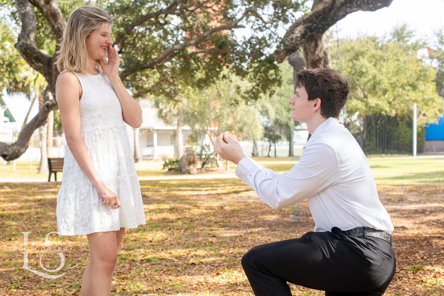 Romantic outdoor photoshoot under oak trees in a park setting.