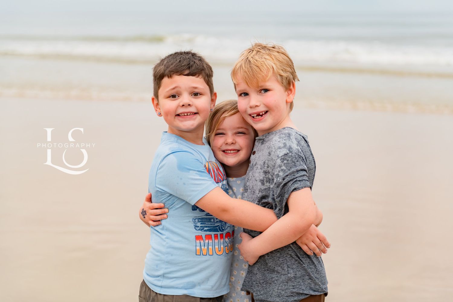 Children sharing joyful moments and embracing on the beach.